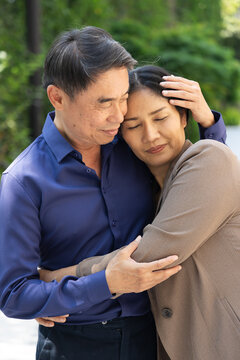 Happy smiling lovely Asian senior couple, elderly husband and wife hugging each other in urban park with good quality of life togetherness after retirement, real human, real people model