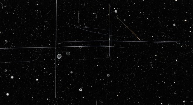 Abstract black background with white dust particles, scratches, and grunge texture, resembling an old film overlay or distressed surface.