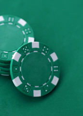 Naklejka premium Green casino poker chips on green gaming table close up. Few amount of green casino chips