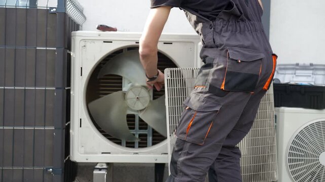 Technician removing front cover grille from outdoor heat pump unit during residential HVAC service. Concept of heat pump maintenance repair and home heating and cooling