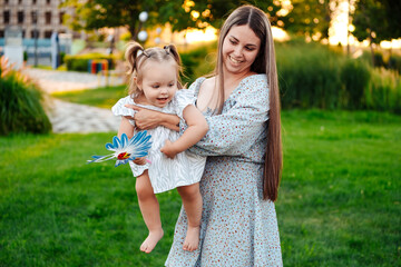 Obraz premium mom and child playing on a green lawn in the park in the summer, having fun together, mother and small child walking in the summer, playing on the grass