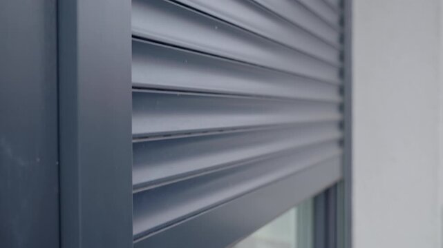 Close-up of modern exterior window with metal roller shutter moving down. Concept of home security privacy control and residential architecture detail