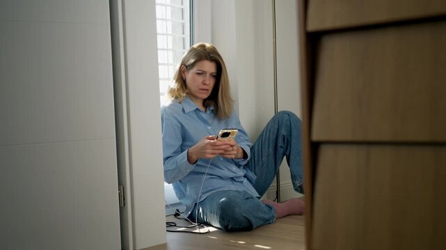 Woman sitting in the corner of the room with her smartphone.