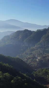Scenic view of lush green mountains and valleys in the countryside near Bontoc and Sagada, Philippines, under a clear blue sky.