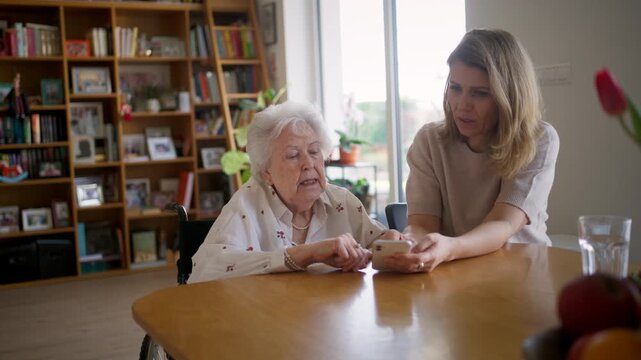 Daughter helping elderly mother use smartphone and online banking.