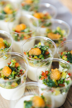 Elegant appetizer cups featuring a creamy white mousse base topped with a vibrant vegetable brunoise of peppers and cucumber, finished with a delicate dollop of golden fish roe for gourmet catering.