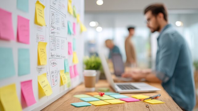 Creative team collaborating on agile project management using sticky notes and wireframes in modern office