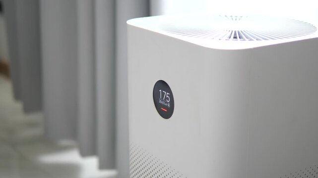 Modern white air purifier with digital display showing high PM 2.5 dust levels in a room for healthy home and pollution concept