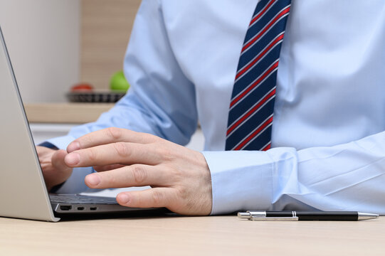 A man elegantly dressed in a shirt and tie is typing on a computer keyboard, working