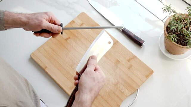 Sharpening a kitchen knife with a honing rod on wooden cutting board. Knife maintenance and culinary precision concept. Ideal for cooking and kitchen tool content. Clean, organized workspace. Daylight