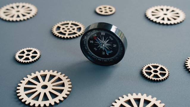 Black magnetic compass positioned between wooden gears symbolizing strategic direction and business navigation.