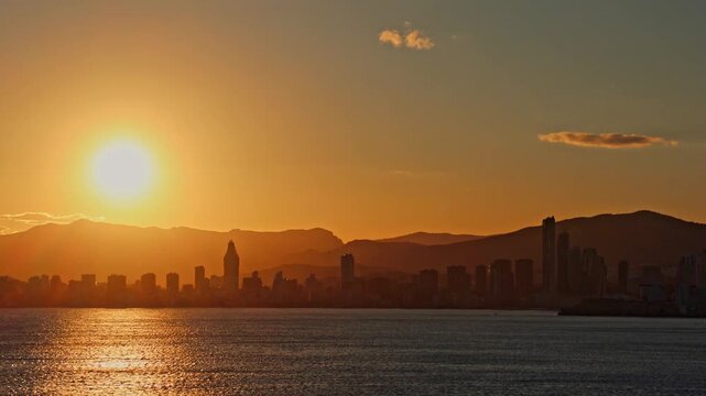 Majestic sunset over the Benidorm skyline in Spain. Skyscrapers against a vibrant sky with the Mediterranean Sea in the foreground.