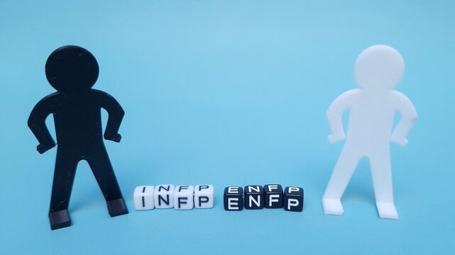 whte and black plastic blocks spelling INFP and ENFP with small toy figures, isolated on blue background. INFP and ENFP are 2 of the 16 personality types identified by the Myers-Briggs Type Indicator 