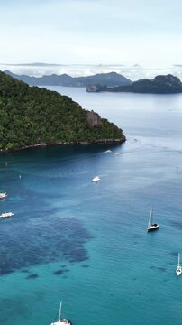 Aerial drone view of calm turquoise waters and scattered boats cruising through Bacuit Bay in El Nido, Palawan. Vertical