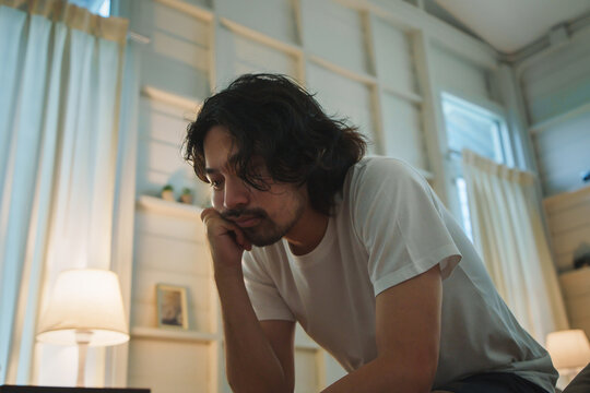 Japanese man feeling stressed and insomnia sitting in bedroom at night