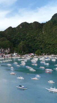 Aerial drone view of traditional banca boats anchored in the turquoise waters of Bacuit Bay near El Nido, Palawan, Philippines. Vertical