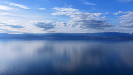 Fototapeta premium Aerial View 4K of Lake Leman with Cloud Reflections on Calm Water and Minimalist Landscape