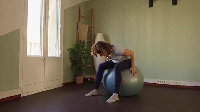 Woman performing pelvic tilt exercise on stability ball