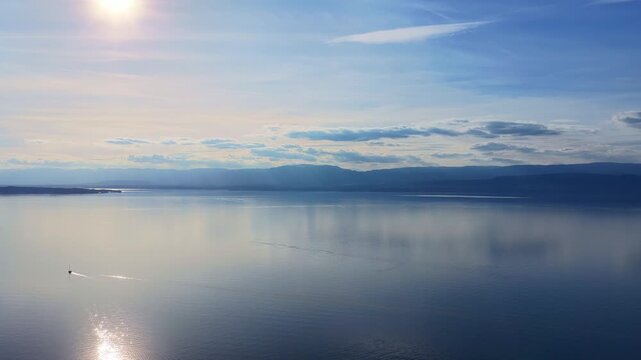 Aerial Drone 4K Flying Over Lake Leman with Boat Leaving Trail on Calm Water and Soft Sun Reflections