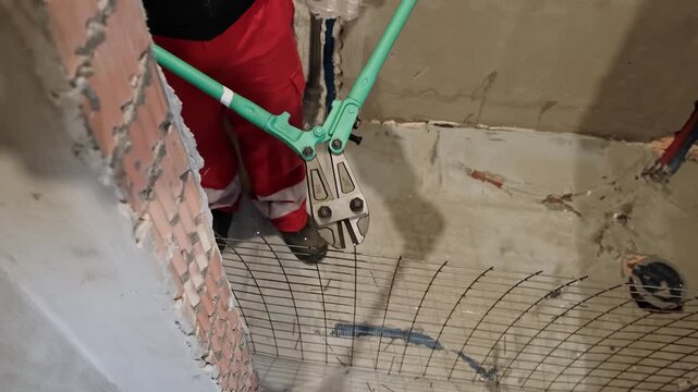 Heavy-duty bolt cutters cutting through a metal wire mesh in an industrial environment. Large scissors for steel. Hands equipment. Handle work is on construction site. Top view. HQ 4k footage.