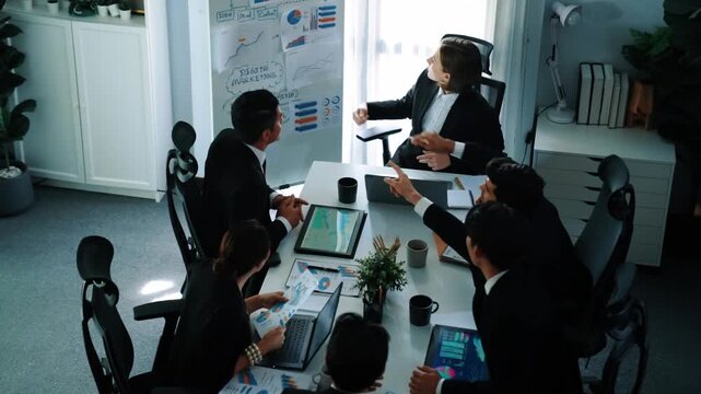 Top view of smart manager project pointing at whiteboard with mind map and financial graph and explain marketing idea while diverse investors listening and analyze stock investment chart. Directorate.