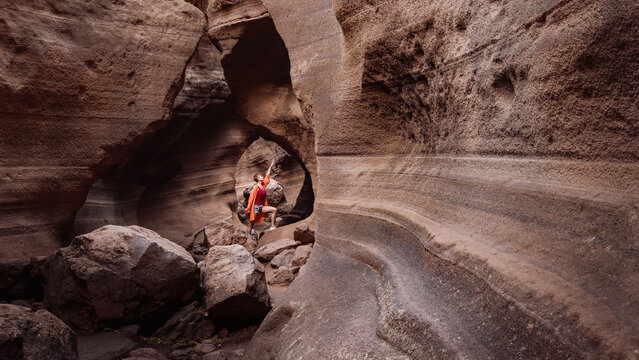 Woman exploring narrow canyon with curved smooth walls, Barranco de Las Vacas, Gran Canaria, Spain