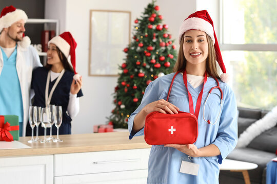 Female doctor in Santa hat with first aid kit at hospital on Christmas eve
