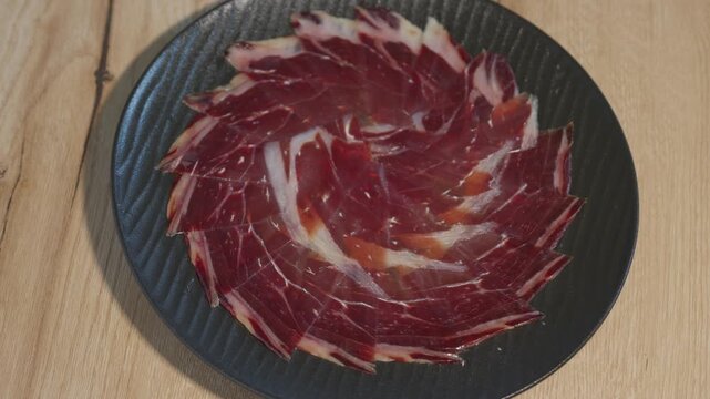 Iberian ham from guijuelo top down view of a spinning plate with slices of delicious dry cured iberian ham. Traditional gourmet spanish tapa or appetizer