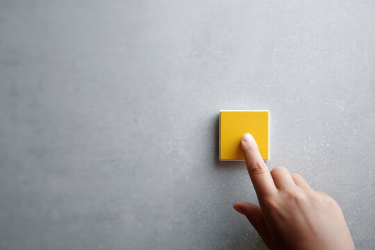 hand pressing yellow accessibility assistance button on wall public space inclusivity concept