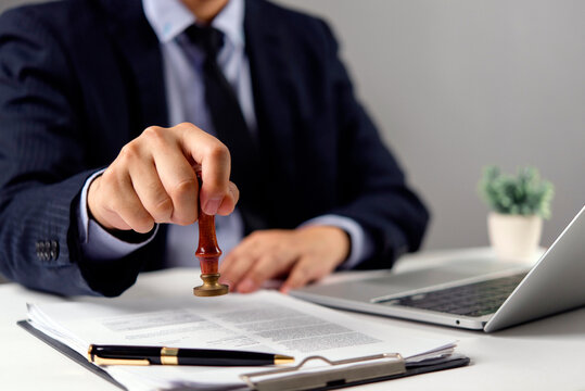 Businessman stamping document approval desk office official certified legal contract agreement validate authority notary compliance corporate business.