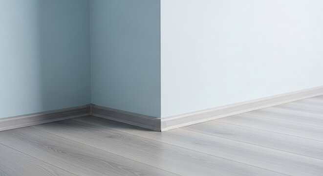 Light grey laminate flooring meeting a light blue wall in an interior corner