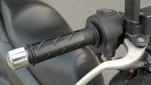 Detail of a black motorcycle throttle grip and silver brake lever for safety inspection