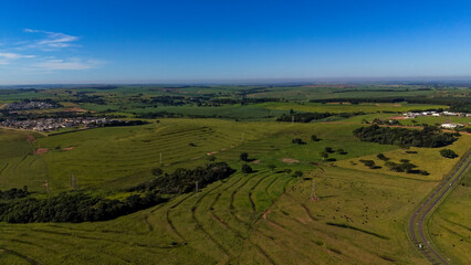 Naklejka premium Aerial view of a serene landscape with green fields and a clear blue sky