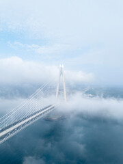 Fototapeta premium Vertical aerial view of Yavuz Sultan Selim Bridge pylon rising through a thick sea of white clouds in Istanbul. Ethereal and misty Bosphorus landscape at Poyrazkoy. Modern engineering in the sky. Atmo