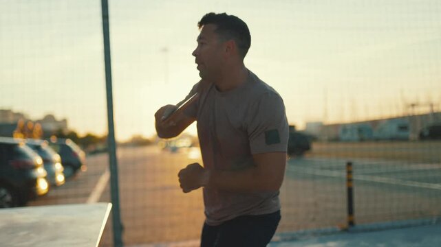 Young man celebrating winning a ping pong match outdoors at sunset
