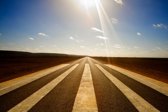 Long Straight Road with Sun Overhead. Concepts of Travelling into a Bright Future, Moving Forwards. Good times ahead, the Best is Yet to Come.