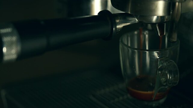 Glass mug under an espresso machine ready to brew