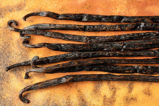 Whole vanilla beans on an orange surface 