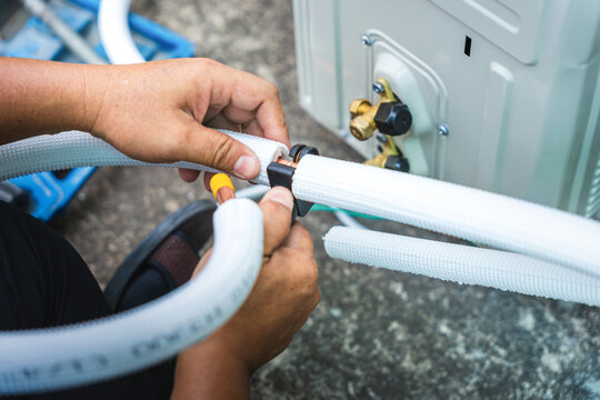 Technician hands installing insulation on air conditioner copper pipes, HVAC worker preparing refrigerant lines for outdoor AC unit installation, Man installing split system air conditioning pipes