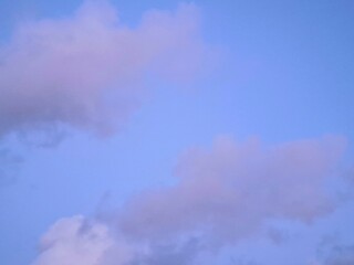 Obraz premium Beautiful soft blue sky with fluffy white and purple tinged clouds at dusk. Peaceful evening atmosphere, perfect for nature backgrounds, weather themes, and spiritual or calm concepts.