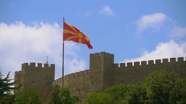Macedonian flag on flagpole waving on wind, near Tsar Samuel's Fortress in Macedonia. Flag Waving Macedonian Flag Flying. Macedonian flag flying high on pole against blue sky background on clear day