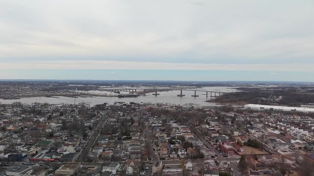 Aerial view of a bridge over a river in a residential area of perth amboy, new jersey, showcasing the victory bridge and urban landscape under a cloudy sky during winter