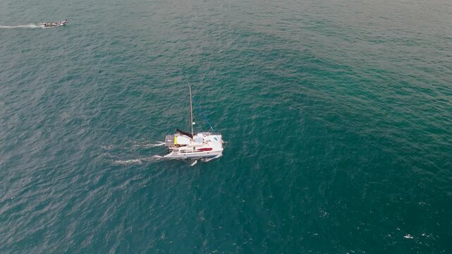 A white yacht sails in the blue ocean among endless waters, aerial view