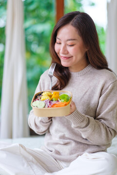 Vertical portrait image of a woman eating vegetables salad at home, Vegan, Clean food, dieting concept