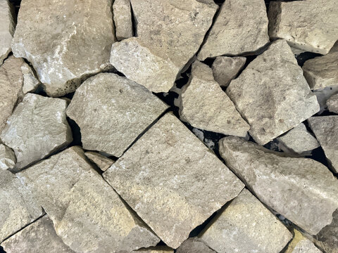 Close up of natural random cut grey beige cobble stone or flag stone gravels. Rough flagstone and gravel stacked randomly, for floor or wall finishes. Seamless background texture.    