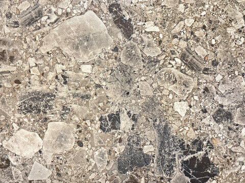 Close up of random cut natural flattened stone with small gravels, grunge, and dirt pattern. Grey and black terrazzo color. Seamless background texture.