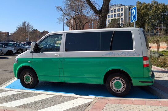 Vista lateral de una furgoneta de pasajeros Volkswagen Caravelle aparcada en una plaza reservada para minusv&aacute;lidos en Madrid, Espa&ntilde;a