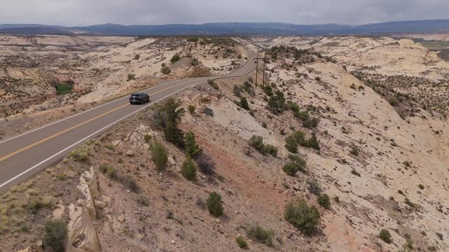 Fly over remote desert road in Utah Hwy 12 as cars pass under