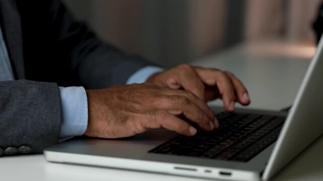 Close up of hands of businessman typing  scrolling on laptop keyboard. Professional working on computer, entering text, managing information during daily business tasks at workplace Concept