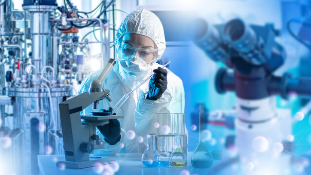 Biotechnology research, pharmaceutical lab. Scientist works with microscope and pipette near bioreactor, conducting sterile experiments and analyzing biological samples.